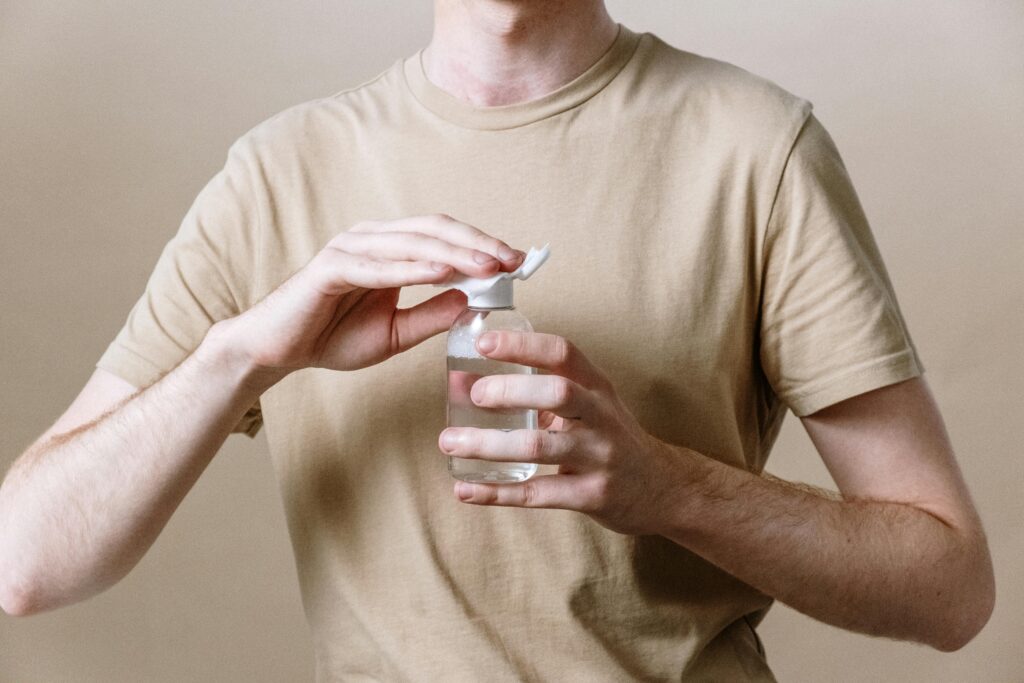 Adult male opening a bottle of micellar water, representing a skincare routine.